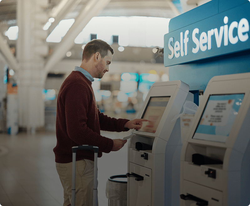 A man standing in front of self service machines.