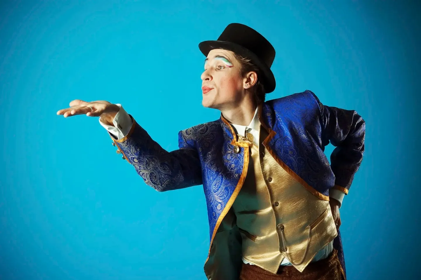 A performer in a blue jacket and top hat gesturing dramatically.