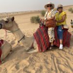 Two people riding a camel in desert.